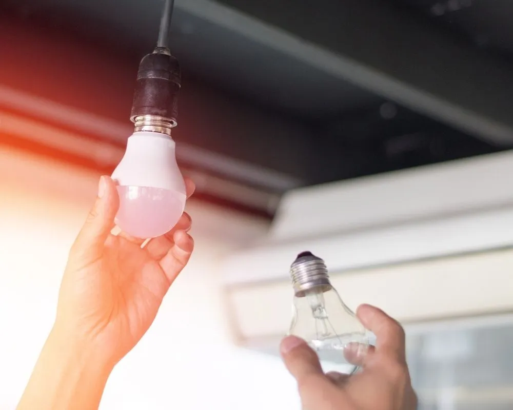 A person replacing a light bulb in a socket.