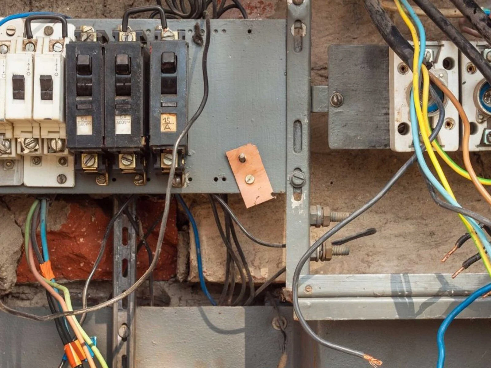 Electrical circuit components mounted on a wall, including circuit breakers and tangled wires.