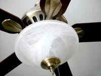 A ceiling fan with light fixture and wooden blades.