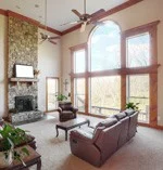 A spacious living room featuring large windows, a stone fireplace, and comfortable seating.