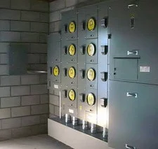 A wall-mounted bank of electrical meters within a concrete structure.