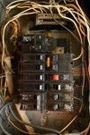 An old electrical circuit breaker panel with visible wires.